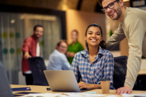 woman and man looking at a laptop in a shared workspace