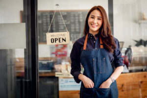 small business woman standing by open sign